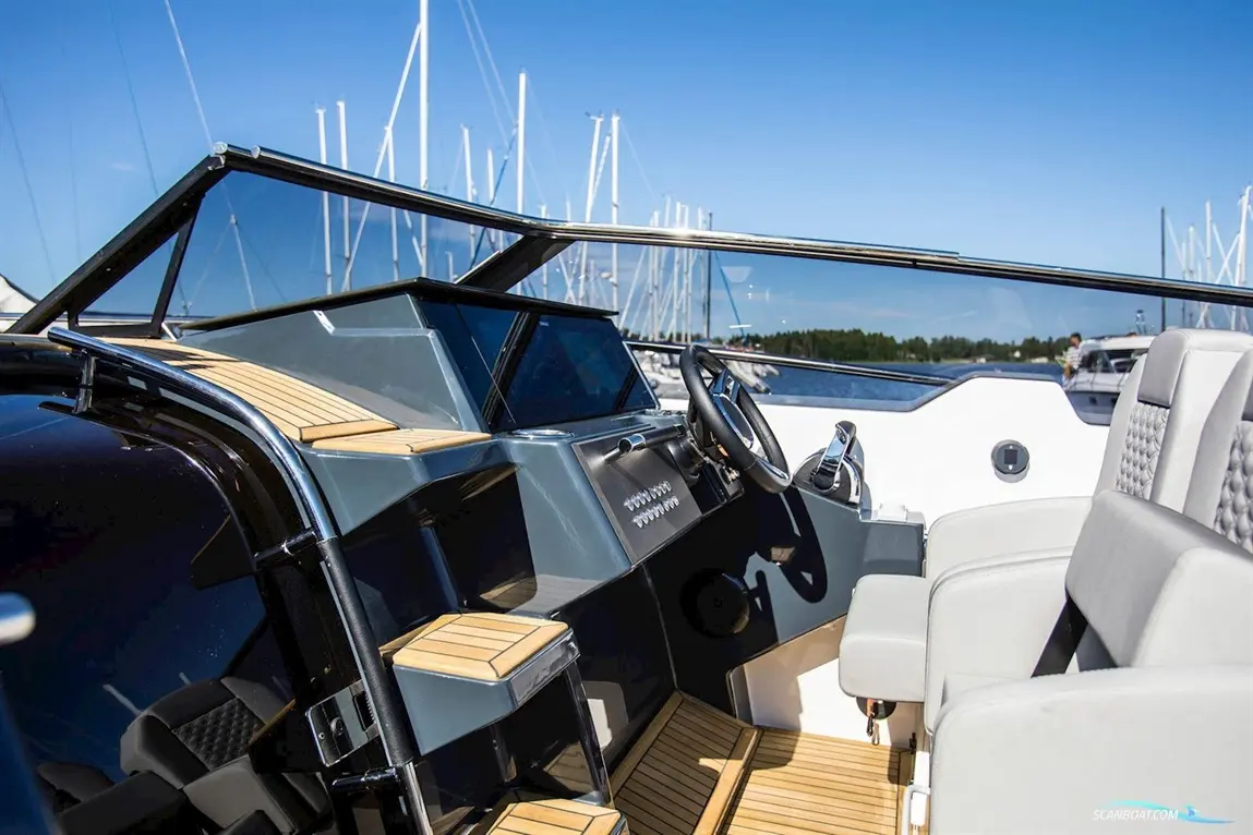 Sleek boat interior with a modern dashboard, steering wheel, and padded seats, overlooking a marina under blue skies.